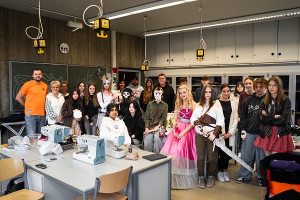 Gruppenbild mit Barbie: Von links: Dennis Reimer (Rapschool NRW) , Eva Ruthe (Dozentin), Karin Hoppe Boske (Lehrerin Realschule Lemgo), achte von links: Dorothee Meier (Schulleitung Realschule Lemgo), Daniel Schneider (Leitung Rapschool NRW), zehnter von rechts: Thomas Mahlmann (zdi-Zentrum Lippe.MINT) mit den jungen Cosplayerinnen und Cosplayern. - © Lippe Bildung eG