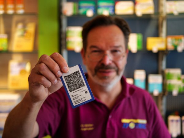 Oliver Müller, Inhaber der Bahnhof-Apotheke in Detmold, zeigt die Immunkarte. Wer seinen Impfnachweis gerne in Kartengröße bei sich tragen möchte, kann sich diese kostenpflichtig bei einigen Apotheken ausstellen lassen. - © Till Sadlowski