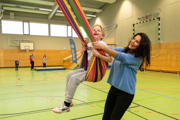 Schauspielerin Mariella Ahrens ist zu Gast in der Topehlen-Schule, hier gibt sie in der Sporthalle Noah Anschwung beim Schaukeln. - © Christian Weische/Bethel