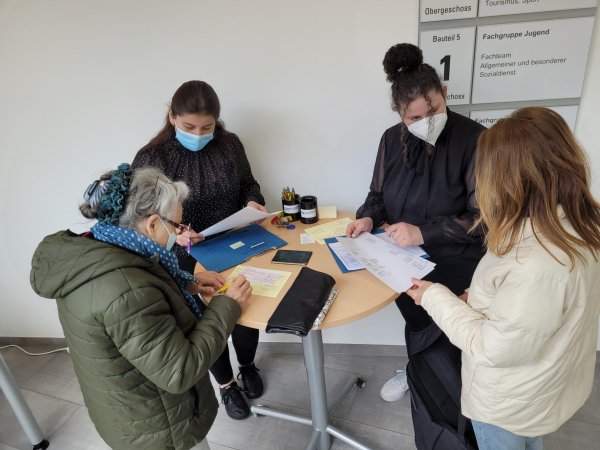 Ebru Birincioglu (Zweite von rechts) und ihre Kollegin Cigdem Önen haben zwei Schecks vorbereitet, die sie an ukrainische Flüchtlinge übergeben. Das Sozialamt Lage hatte schon kurz nach der Ankunft der ersten Flüchtlinge eine einfache Geldausgabe mit der Sparkasse am Markt organisiert. Es ist eine Aufgabe von vielen, die zusätzlich bewältigt werden müssen. - © Astrid Sewing