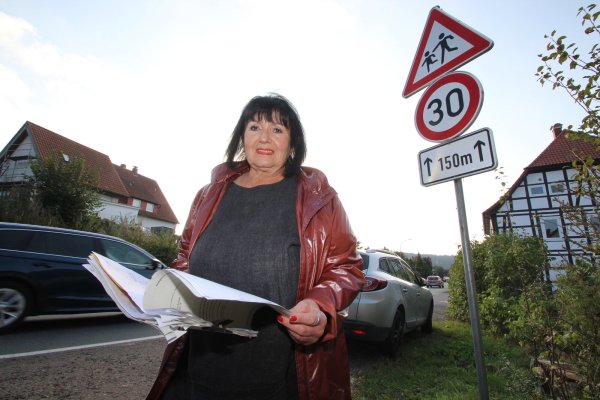 Daisy Krüger steht vor dem fraglichen 30er-Schild in der Ortsdurchfahrt Erder. Hier oder - nach Darstellung des Kreises - deutlich weiter die Straße hinunter wurde sie geblitzt. In der Hand hält die Kalldorferin den Aktenordner mit ihren Unterlagen zu dem Fall. - © Jens Rademacher