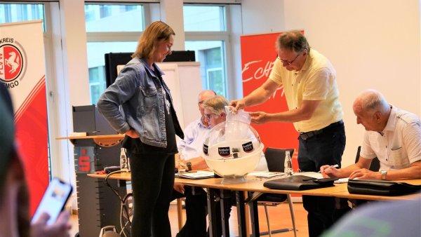 Kim Marie Kreilaus verfolgt gespannt, wie Bernhrad Brandt den Lostopf befüllt. Die junge Dame vom VfL Lieme fungierte auf der Arbeitstagung des FuL-Kreises Lemgo als Glücksfee und zog die Lose für den Kreispokal. - © Jörg Hagemann