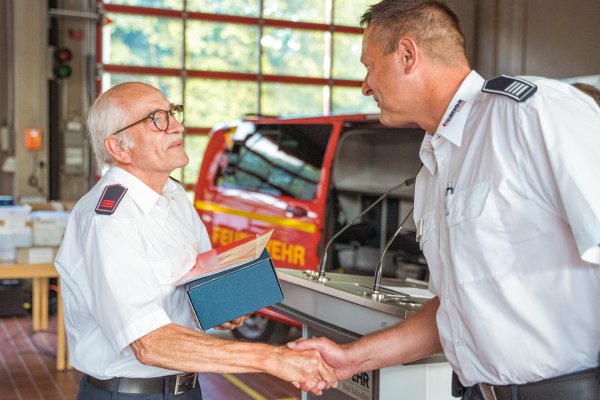 Der kommissarische stellvertretende Leiter der Feuerwehr Bad Salzuflen, Christian Drewes, dankt Reinhold Wiesekopsieker für seine 50-jährige Treue zur Feuerwehr. - © FreitagTV