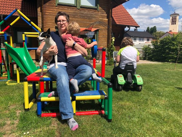 Britta Slavov sitzt mit ihren Kindern und Hund im Garten. - © Sven Kienscherf
