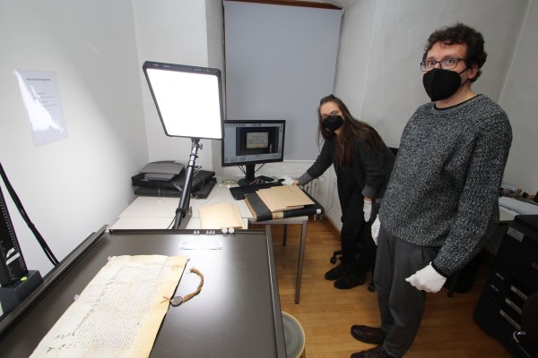 Archiv-Mitarbeiterin Britta Ledebur legt die päpstliche Urkunde von 1390 auf den Spezialscanner. Handschuhe zum Schutz der wertvollen Dokumente (und auch der Hände) sind Pflicht. Stadtarchivar Marcel Oeben ist mit dabei. - © Jens Rademacher