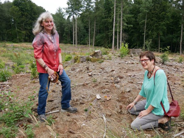 Bronzezeit. Marion Behrend steht am Hügelgrab in Lüdenhausen und zeigt Wilma Gläsker Grabbeigaben, die am Boden liegen. - © Thomas Krügler