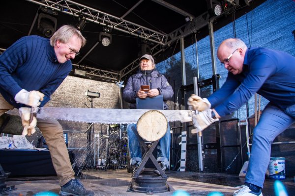 Dirk Tornede (links) vom Heimat- und Verkehrsverein und Bürgermeister Marcus Püster (rechts) machen den Auftakt beim Sägewettbewerb auf dem Schlänger Markt. Friedel Gingert nimmt die Zeit. - © Raphael Bartling