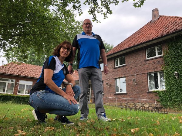 Silke Rehmeier und Detlev Siewert vom Vorstand der Turngemeinschaft Schötmar stehen auf dem Rasen vor der Festhalle. Rechts ist das 90 Jahre alte Gemäuer zu sehen, links hinten der Anbau, der später dazu kam und in dem sich der kleine Saal befindet. - © Sven Kienscherf