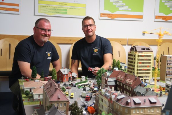Das ist keine Spielerei. Mit diesem, wie eine Stadt im Miniaturformat aussehenden Planspiel können Ralf Solle (l.) und Sebastian Köster dem Feuerwehrnachwuchs das taktische Vorgehen bei Einsätzen im Ernstfall erläutern. Foto: Knut Dinter - © Knut Dinter