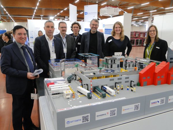 Jannis Graunke (Mitte) und sein Entwicklerteam vom Fraunhofer-Institut Paderborn haben ein anschauliches Lego-Modell aufgebaut, mit dem die Messebesucher Anwendungen von Automation und künstlicher Intelligenz studieren können. Teilnehmer der FMB-Projektvorstellung von links: Martin Strauch, Bürgermeister Dirk Tolkemitt, Diplomingenieur Josef Hilsmann, Jannis Graunke, Wolfgang Marquardt, Almut Rademacher und Tanja Waglöhner. - © Hajo Gärtner
