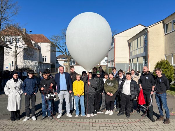 Der Ballon ist gefüllt, gleich geht's ab in den Himmel: Die Verantwortlichen vom zdi-Zentrum Lippe.MINT und von der Stratoflights GmbH & Co. KG mit den Schülerinnen und Schülern. - © Lippe Bildung