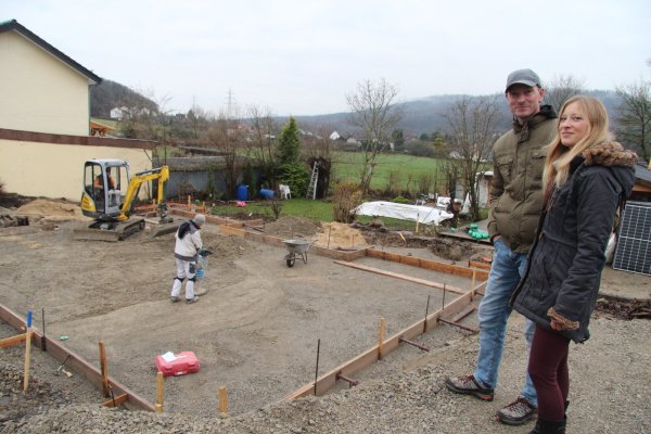 Svantje und Lars Heidemann stehen am Rand der Baugrube, wo zwei Arbeiter gerade den Untergrund für das Betonfundament ihres neuen Hauses vorbereiten. Bis Ende der Woche soll es gegossen sein. - © Dieter Asbrock