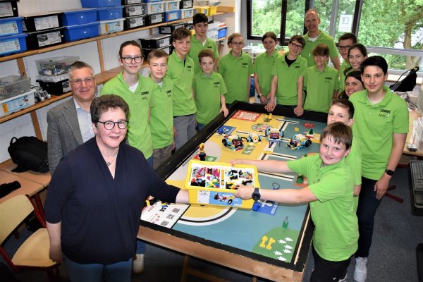 Dr. A. Heinrike Heil (von links), Geschäftsführerin der LIFT-Stiftung, übergibt im Beisein von Schulleiter Michael Hanke und dem Leitungsteam Sandra Däubner (4.von rechts) und Gunnar Jürgens auf der Haar (8. von rechts) die neuen LEGO-Roboter an die Roboter-AG. - © Hermann-Vöchting-Gymnasium