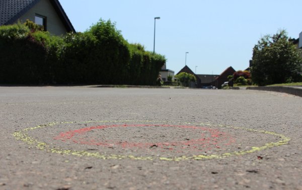 34 gelb-rot markierte Kreise (das Bild zeigt einen davon) auf der Straßendecke in der Salzufler Sackgasse deuten genau auf die Stellen hin, wo die Spurensicherung am Einsatzort Patronenhülsen sichergestellt hat. Fünf Kugeln trafen den damals 19-jährigen Fahrer. - © Janet König