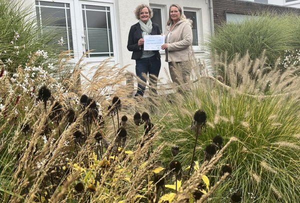 Gaby Teske (rechts) als glückliche Gewinnerin des Fotowettbewerbs „Rettet den Vorgarten" erhält von Dr. Petra Bloom (Landesverband der Gartenbauvereine NRW) einen symbolischen Scheck der drei Verbände über 1000 Euro in ihrem Vorgarten. - © Landesverband der Gartenbauvereine NRW