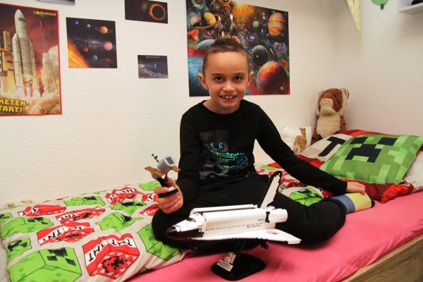 Der achtjährige Vincent sitzt in seinem Kinderzimmer. Er interessiert sich sehr für Astronomie und Raumfahrt. - © Nadine Uphoff