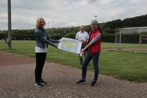 Auf dem Sportplatz in Langenholzhausen präsentieren Ute Seidemann (links) und Cornelia Rehse zusammen mit Bügermeister Mario Hecker die Pläne für den Umbau - falls die Fördermittel kommen.  - © Carolin Brokmann-Förster