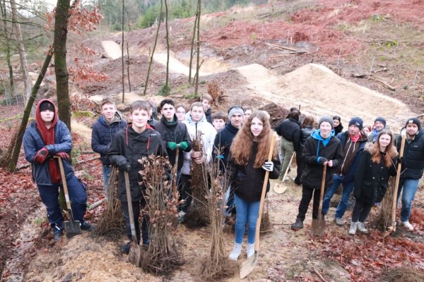 Mit Begeisterung machten sich die 30 Schülerinnen und Schüler der Klassen 9 und 10 ans Werk. Hinter ihnen sind die fast fertigen Mountainbike-Strecken zu erkennen. - © Knut Dinter