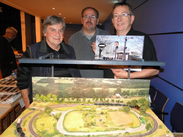 Große Ingenieurskunst auf kleiner Spur: Der "Spur-N-Stammtisch" aus Rimbeck präsentiert sein "Ländliches Eisenbahnidyll" im Schulzentrum Werreanger zum Vergnügen der Eisenbahnfreunde Lippe, die im Gegenzug auf ihren schicken Hochglanzkalender 2024 verweisen. Von links: Hans-Joachim Rüssel, Stefan Schulz und Dirk Schneider. - © Hajo Gärtner