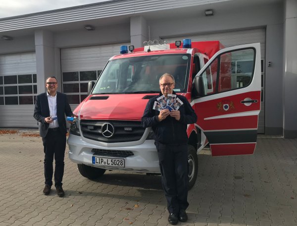 Bürgermeister Markus Baier und Feuerwehrchef Klaus Wegener zeigen die Informationen der Unfallkasse NRW für Ersthelfer, die bei der Freiwilligen Feuerwehr Lemgo im Einsatz sind.  - © Alte Hansestadt Lemgo
