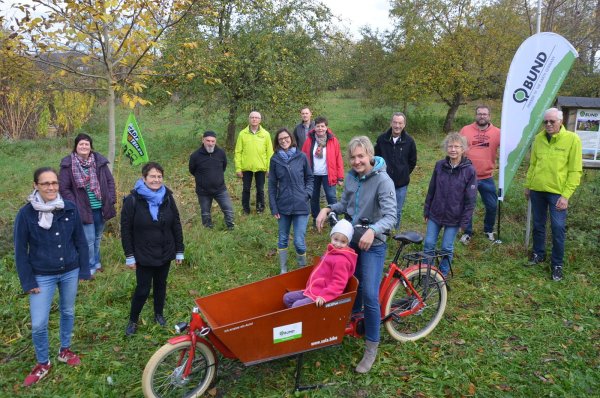 Harald Kohls (Bild rechts) und seine BUND-Mitstreiter kümmern sich unter anderem um die Pflege der Streuobstwiesen im Ortsteil Werl. Die kleine Layana Lutterbeck ist vom Sala-Lastenrad ganz begeistert. - © Georg Kälble