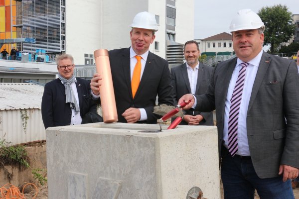Thomas Lammering, 1. Technische Beigeordnete des Bürgermeisters, Klinikum-Geschäftsführer Dr. Johannes Hütte, Aufsichtsratmitglied Carsten Möller und Landrat Dr. Axel Lehmann (von links) zementieren die „Bombe" mit den Unterschriften aller Teilnehmer ein. - © Janet König