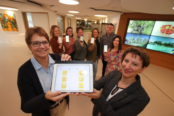 Im Vordergrund freuen sich (von links) Sabine Beine, Verwaltungsvorständin beim Kreis Lippe und Cosmina Ahrweiler, Kommunalen Integrationsmanagement . Im Hintergrund präsentieren (von links) Laura Estevo, Stadt Detmold, Julietta Meierkord, Jobcenter Lippe, Alexandra Steeger und Jessica Keitel, Kommunales Integrationszentrum des Kreises Lippe, Daniel Kanthak, Stadt Detmold, und Ilka Gräber, Netzwerk Lippe, die App. - © Kreis Lippe