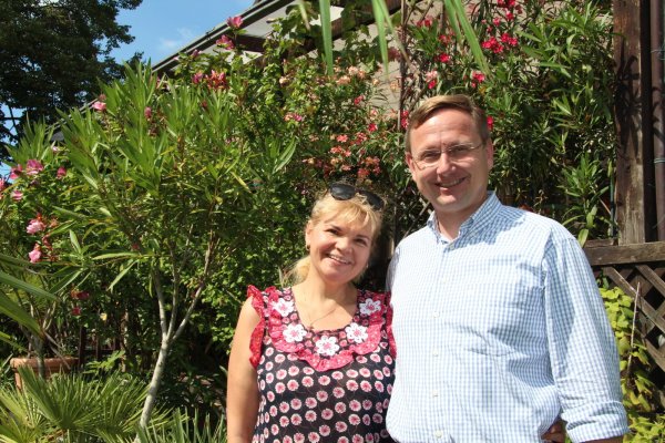 Andreas Wulf steht mit seiner Frau Lolita im Garten vor der Terrasse, an der der Oleander blüht. Die Zucht der Pflanzen sowie die Gartenarbeit gehören zu seinen Hobbys. - © Nadine Uphoff