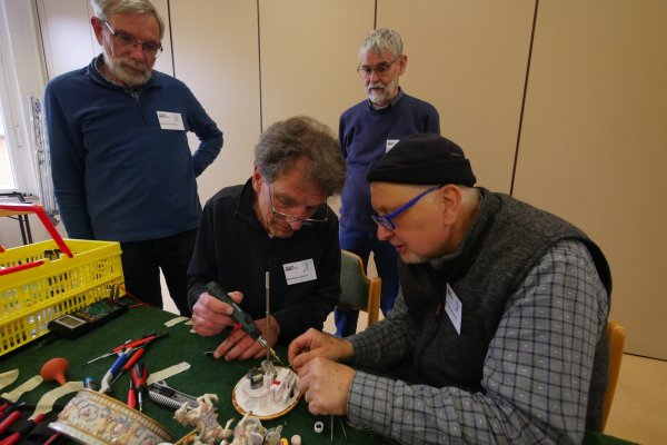 Matthias Rulle (links) und Ulrich Berghahn löten die Elektrik einer alten Spieluhr. Bernd Stritzke (ganz links) und Hans-Alberg Capelle geben hilfreiche Tipps. - © Jost Wolf