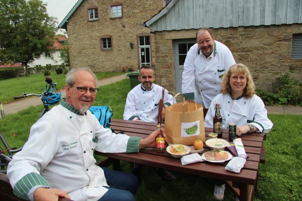 Und das ist drin im Picknick-Paket: Heinrich Oberjasper, Xhafer Salihi, Norbert Lange und Annette Reinking (von links) präsentieren die Leckereien aus der „Schmaus mit Aussicht"-Tüte, die es den ganzen Oktober lang bei den Land-Wirten auf Vorbestellung gibt - © Silke Buhrmester