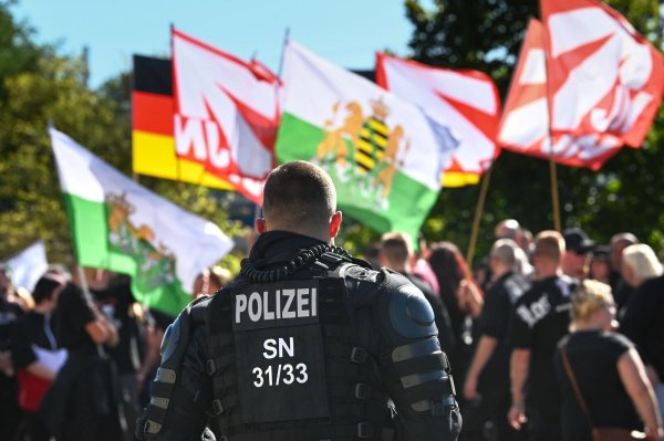 Ein Polizist steht vor einem Fahnenmeer der rechten Szene in Sachsen. Beamte tragen entscheidend zur öffentlichen Ordnung und Sicherheit bei. - © Heiko Rebsch