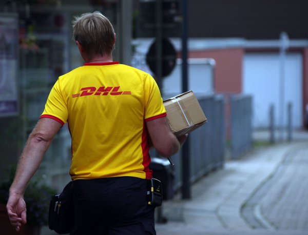 Ein Paketzusteller der von Deutsche Post DHL liefert ein Paket aus. - © Oliver Berg/dpa