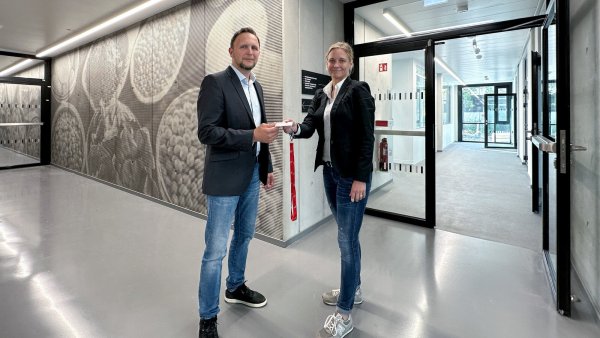 Silke Grote, Planerin und Projektverantwortliche beim Bau- und Liegenschaftsbetrieb, übergibt symbolisch die Schlüsselkarte für den Neubau an Sergej Roth, den Vize-Chef des Dezernats Gebäudemanagement der TH OWL. - © Carsten Pilz/BLB NRW