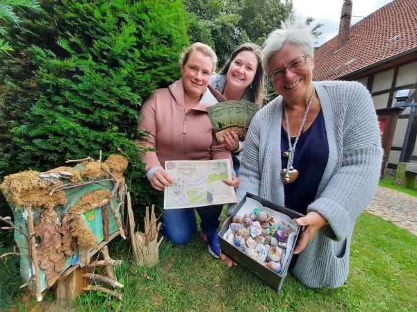 Die Mitarbeiterinnen der Tourist-Information Schwalenberg (von links) Denise Kieslich und Jasmin Baier sowie Künstlerin Marion Weber freuen sich über das große Interesse an der Märchentüren-Expedition. Ausgestattet mit einer Wanderkarte gilt es für die Teilnehmer der Rallye, die Märchentüren zu entdecken und kleine Rätsel zu lösen. Zur Belohnung für die kleinen Abenteurer hat die Künstlerin Steine und Schneckenhäuser bunt gestaltet. - © Michaela Weiße