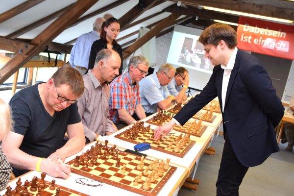 Matthias Blübaum geht von Schachbrett zu Schachbrett und besiegt innerhalb von drei Stunden 21 seiner 22 Gegner. Einem gelingt am Ende ein Remis. - © Karin Prignitz