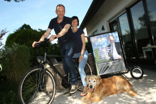 Mit dem Wahlkampf-Fahrrad unterwegs: Jürgen und Andrea Schell mit Familienhund „Benny".  - © Sylvia Frevert