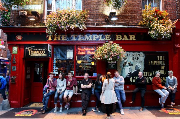 Die "Temple Bar" in Dublin mit einigen Gästen, die vor der Bar etwas trinken und zusammensitzen. - © Roland Marske