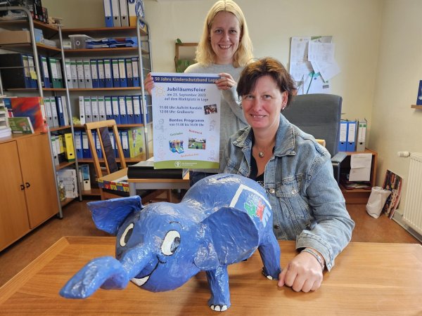 Der Kinderschutzbund Lage hat im September auf dem Marktplatz den 50. Geburtstag gefeiert, Anna Lena Beermann hat das Plakat. Der blaue Elefant, der auf dem Tisch vor Monika Frodermann steht, ist eigentlich eine Spendenbox. Es gibt Grund zur Freude: Die Stadt unterstützt die Einrichtung mit 15.000 Euro. - © Astrid Sewing