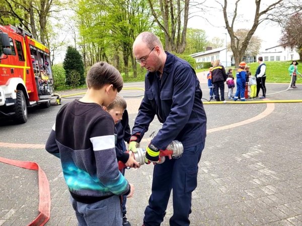 Der Leiter der Jugendfeuerwehr Hörste, Jan-Lukas Schlink, zeigt den Kindern bei einem Spielnachmittag am Kinderheim, wie man Schläuche miteinander verbindet. - © Astrid Sewing
