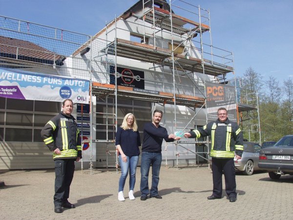 Übergabe der Tankgutscheine vor der Brandstelle über der Werkstatt: Löschzugführer Marcus Hermann, Merle und Holger Ehm sowie Gemeindebrandinspektor Michael Grüttemeier (von links). - © Wulf Daneyko