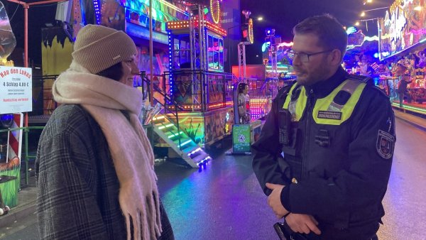 Sebastian Schöps vom Kommunalen Ordnungsdienst unterhält sich mit Andreasmesse-Besucherin Karina Kirst auf dem Kronenplatz. - © Cordula Gröne