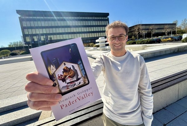 Dominik Gröpper zeigt seinen Roman "Pader Valley" vor der früheren Nixdorf-Zentrale an der Paderborner Fürstenallee. Dort ist heute das Heinz-Nixdorf-Museumsforum untergebracht. - © Jens Reddeker