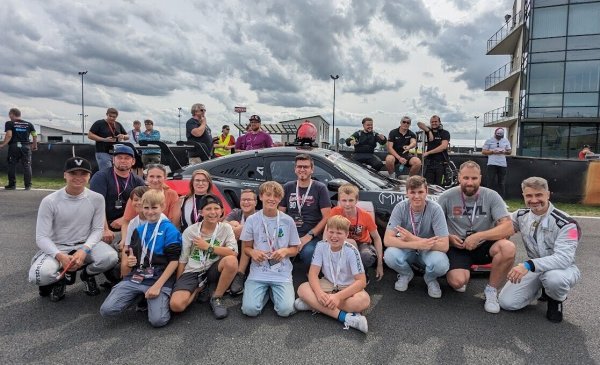 Die Jugendförderung der Stadt Bad Salzuflen zu Besuch in der „Motorsport Arena Oschersleben“: Kinder und Jugendliche des Kartsportvereins MC Wüsten erlebten echtes Rennsportfeeling hautnah gemeinsam mit Rennsporttalent Gian Luca Tüccaroglu (vorne links), Patrick Wulfert (Pädagogische Fachkraft Jugendbereich @on! Stadt Bad Salzuflen, hinten links), Jasmin Hartwig (Jugendwartin MC Wüsten, hinten vierte von links), Sven Hartwig (Jugendwart MC Wüsten, hintere Reihe Mitte), Julian Droste (Jugendförderung Stadt Bad Salzuflen, zweiter von rechts) und Rennfahrer Osman Tüccaroglu (rechts). - © Stadt Bad Salzuflen