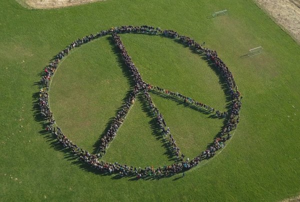 1300 Schülerinnen und Schüler der Karla-Raveh-Gesamtschule haben sich zu einem großen Peace-Zeichen aufgestellt und mit einer Drohne aufgenommen. - © Karla-Raveh-Gesamtschule