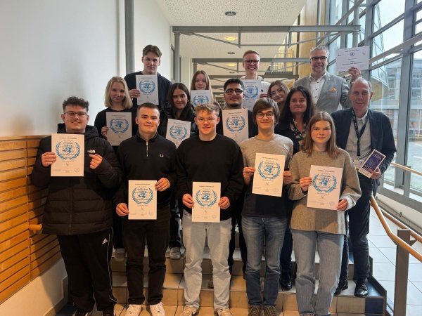 Die Lehrkräfte Ina Rinne, Schulleiter Heiko Jucks und Michael Lohre (von links) mit den Schülern des Hanse-Berufskollegs, die an der Model United Nations teilgenommen haben. - © Hanse-Berufskolleg