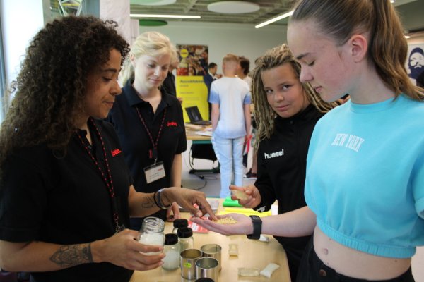 Ramona Richter (links) und Frederike Becker von Jowat zeigen Joshua Roth und Malia Brinkmann Klebstoff-Granulat. Ein Produkt, mit dem der Klebstoffhersteller tagtäglich arbeitet. - © Nico Düllmann