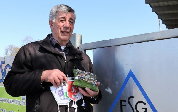 Vor der Eingangstür zum Sportplatz in Pottenhausen hält Ernst-Albrecht Kuhlmann Wimpel und Erinnerungsnadeln aus "50 Jahren Schiedsrichter" in den Händen. - © Oliver König