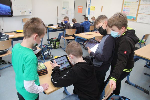 Bei der Suche nach Inhalten für ihr digitales Plakat unterstützen sich die Drittklässler gegenseitig. Ihre Arbeitsergebnisse können sie auch auf den großen Touchscreen beamen. - © Dieter Asbrock