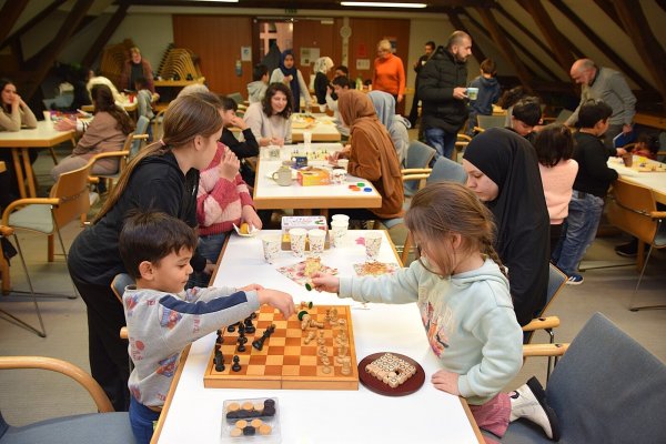 Die Familien nutzen das Spieleangebot im Saal des Bürgerhauses. Das reicht von Schach über Kartenspiele bis hin zu großen Holzspielen. Ehrenamtliche unterstützen und kommen mit den Geflüchteten ins Gespräch. Foto: Karin Prignitz - © Karin Prignitz