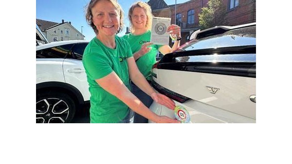 Petra Kuhfus (links) und Claudia Viotto vom BUND Lippe bringen einen Aufkleber auf eine, E-Auto der E-Firmenflotte an, die am „E-Mobility Day“ von Kaeding Anderson in Lemgo präsentiert wurde. - © BUND Lippe